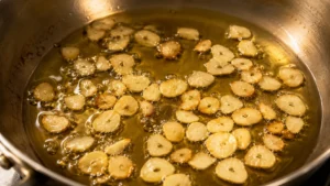 Garlic slices toasting golden in olive oil