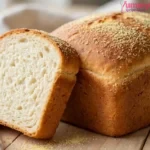 Golden homemade white bread loaf with semolina-dusted crust on a wooden board